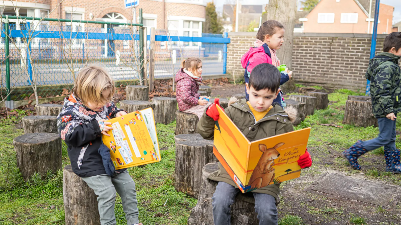 Kinderen lezen buiten op boomstammen