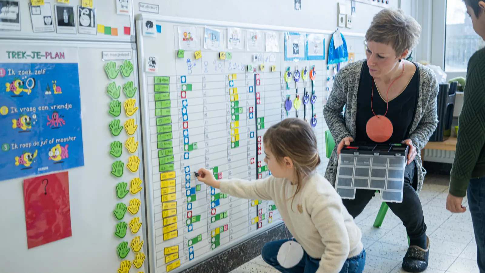 Leerkracht en kleuter aan het planbord