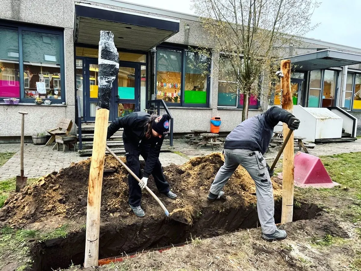 Ouders planten bomen op de speelplaats